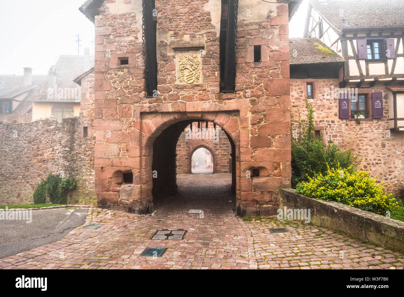 medieval rampart and town gate of village Riquewihr with fog, Alsace, France, touristy village of the Wine Route Stock Photo