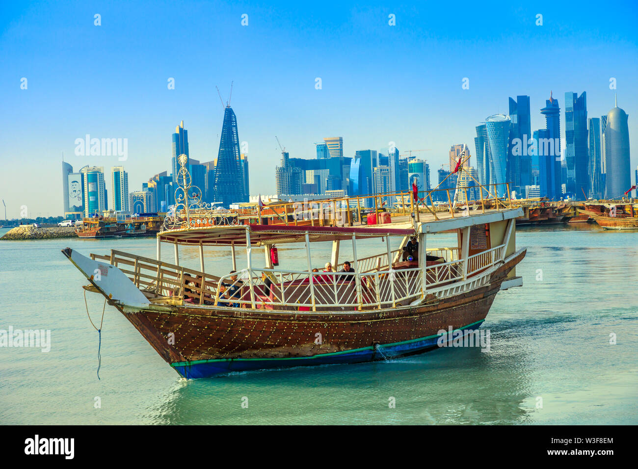 Doha, Qatar - February 23, 2019: people tourists on dhow and seafront of Doha West Bay skyline with Qatar International Exhibition Center, Doha Tower Stock Photo