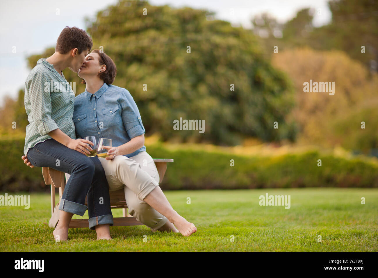 Mid adult couple sitting on a chair and kissing Stock Photo Alamy