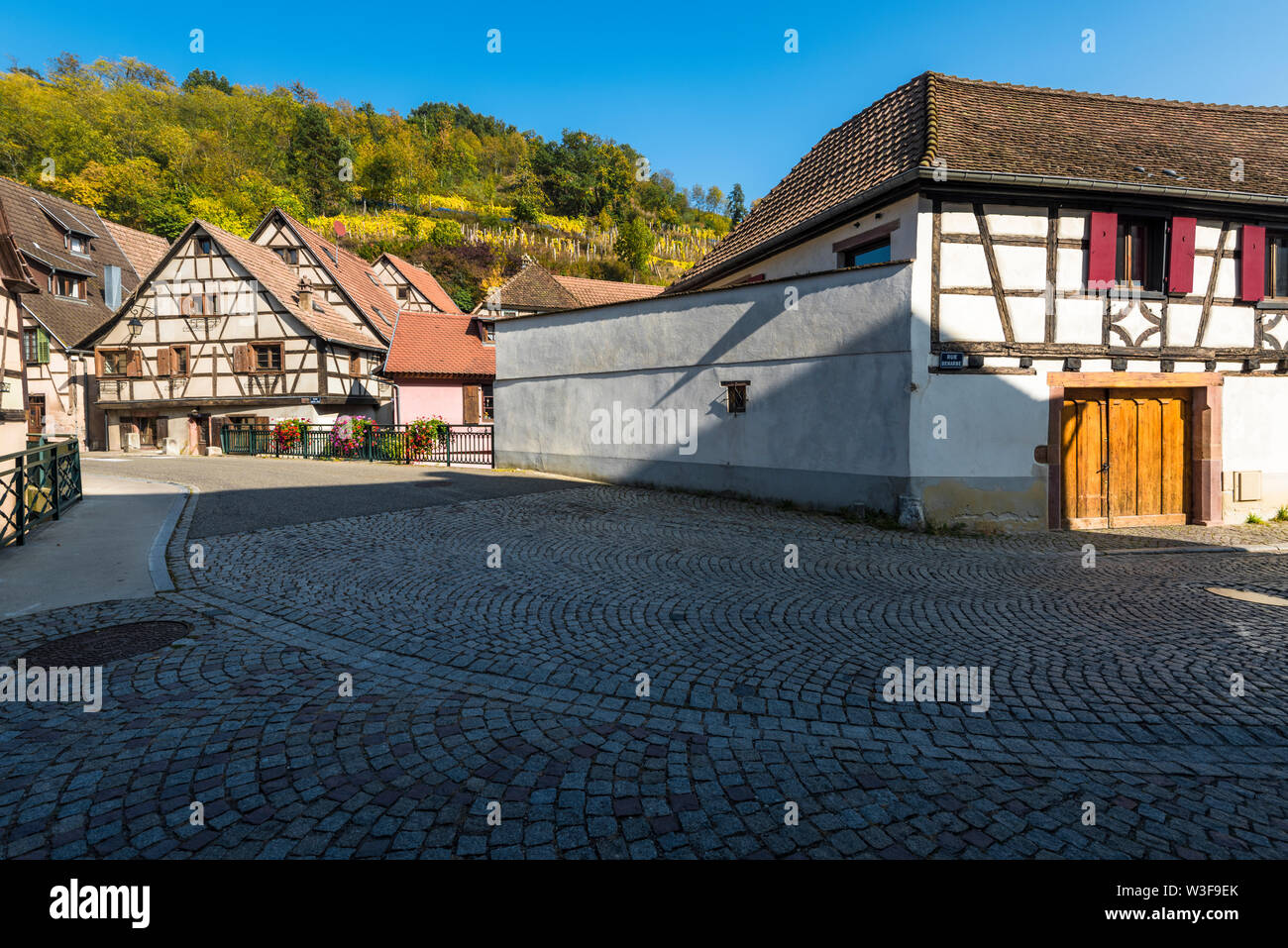 road through the old village Andlau, Alsace, France, half-timbered houses and view to hill with vineyard Stock Photo