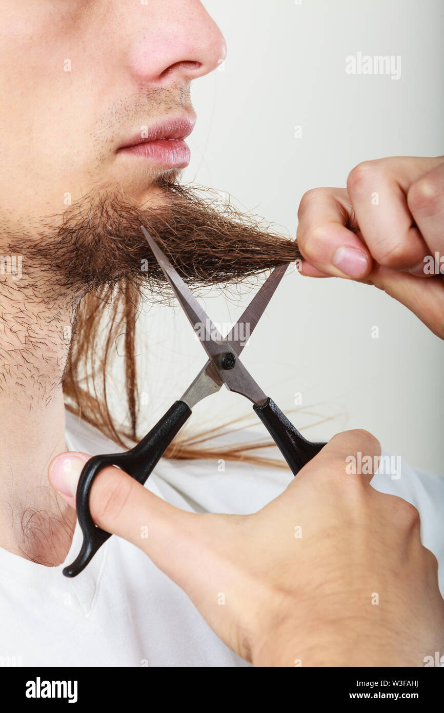 Cut and shave concept. Young man with long beard holding scissors. Part