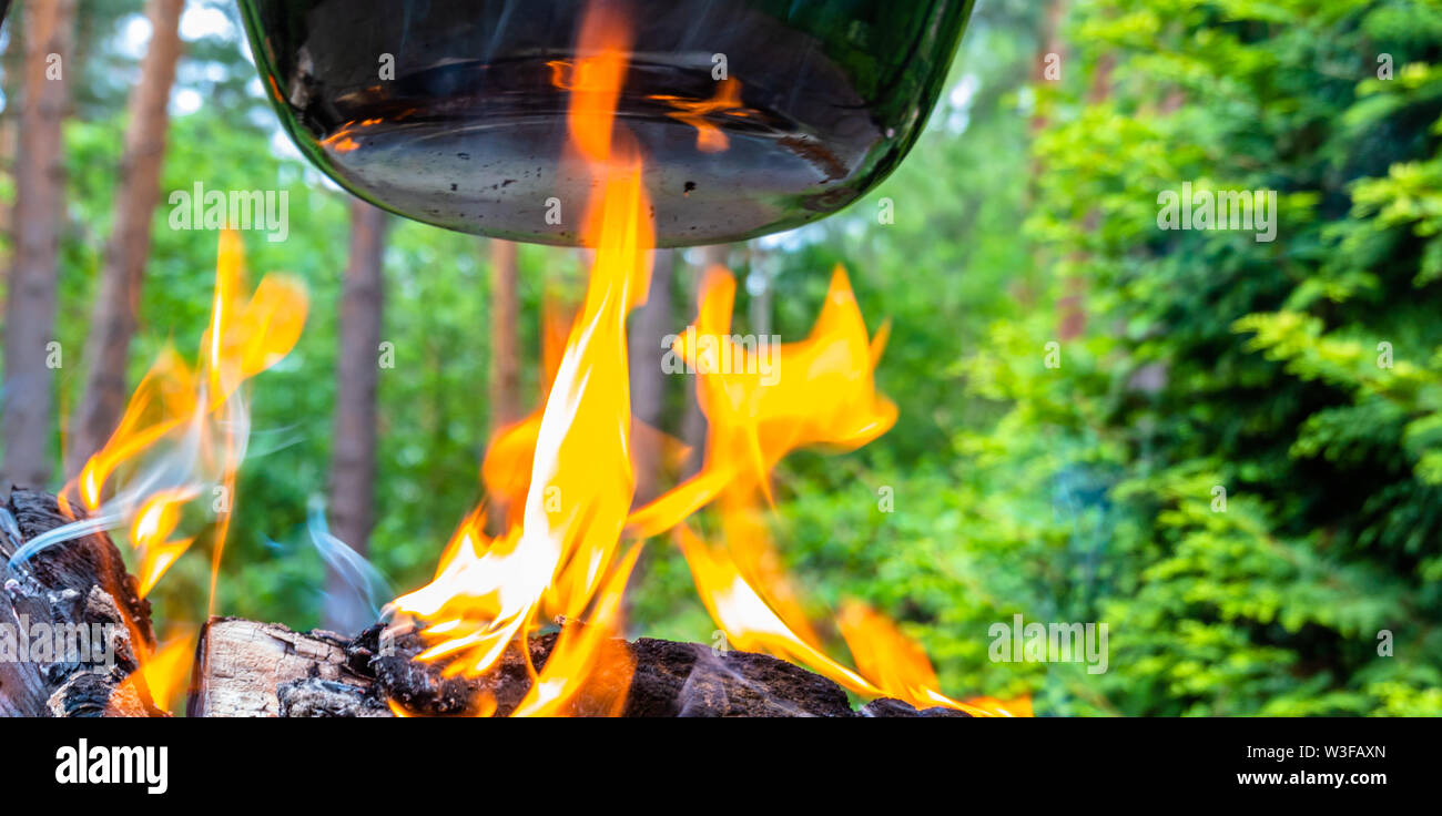 Lambent yellow hot flames of a fire of logs under a large suspended kettle with kettle goulash Stock Photo