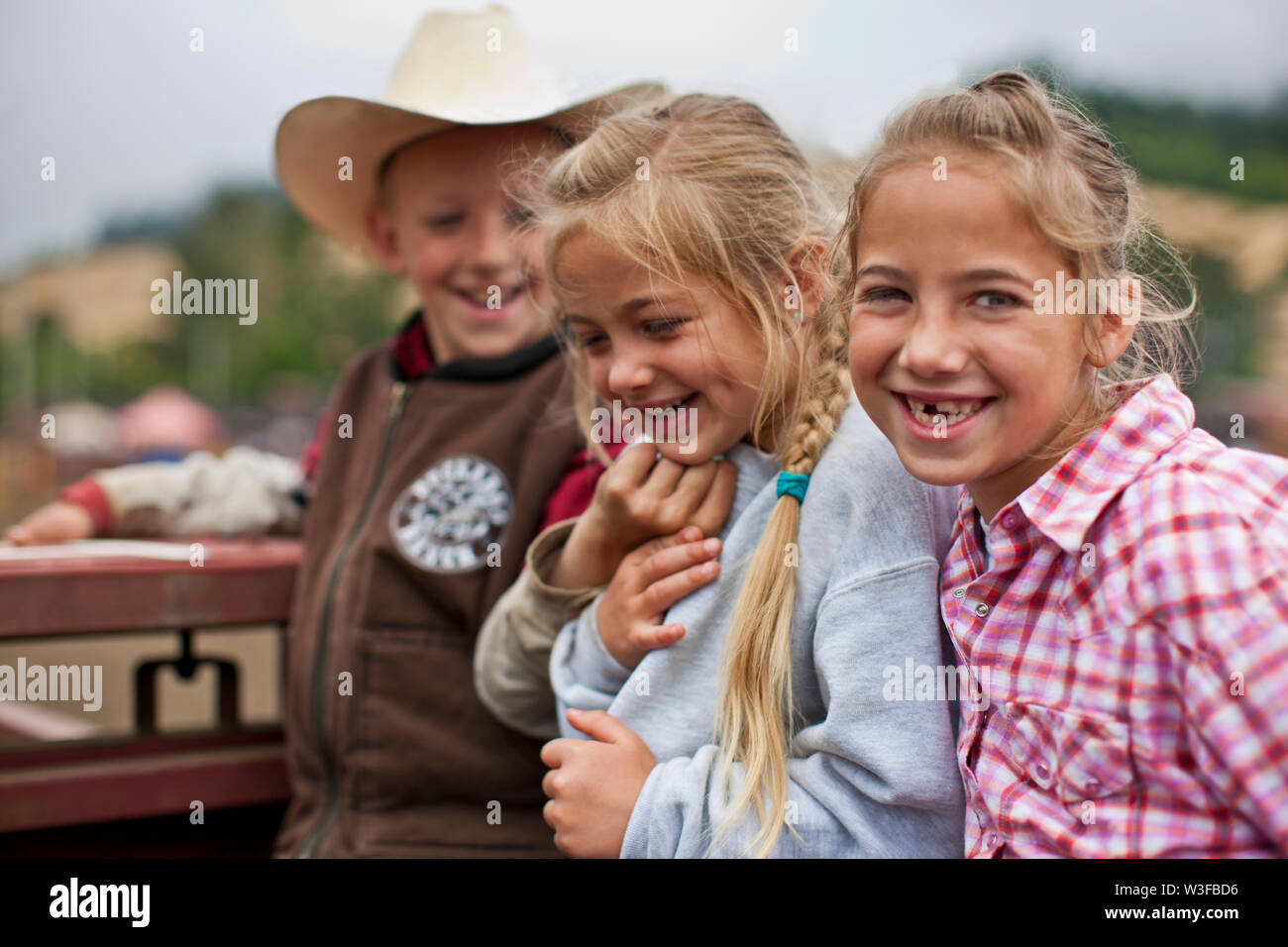 Portrait of three smiling siblings at a ranch. Stock Photo