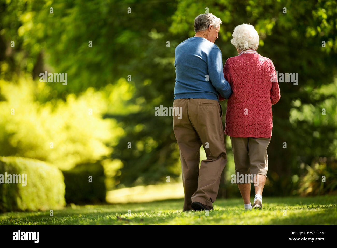 Affectionate elderly couple walk in a sunny garden together Stock Photo ...