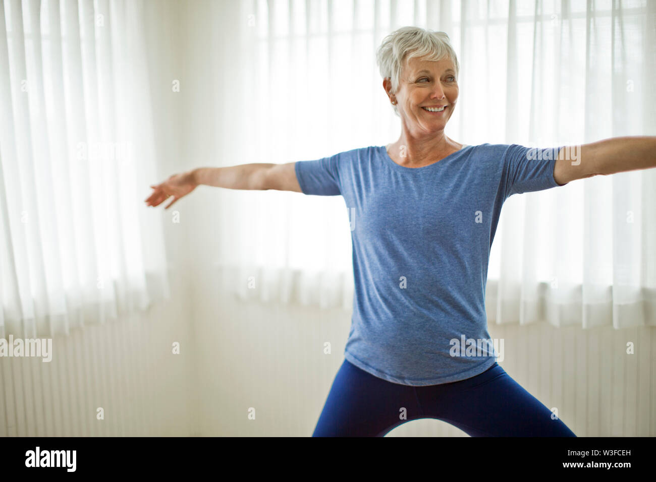 Happy Mature Woman practicing yoga at home. Stock Photo