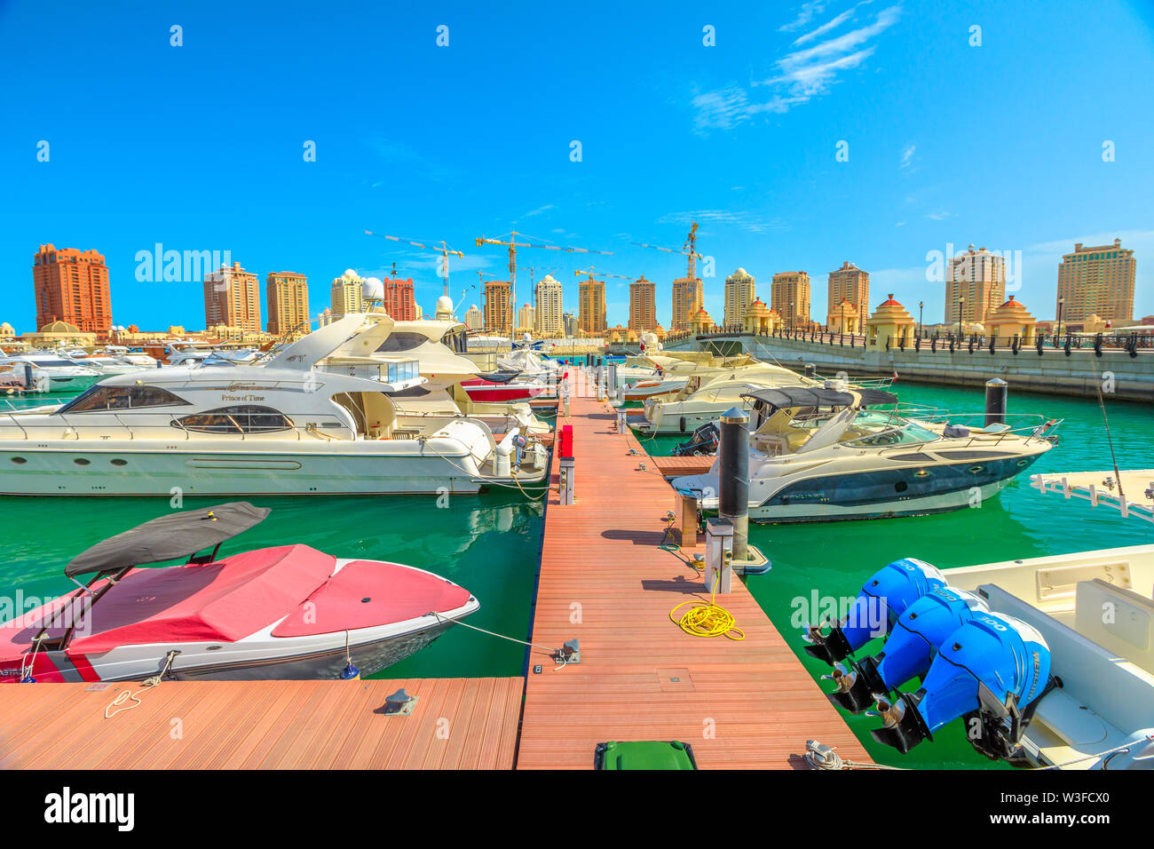 Doha, Qatar - February 18, 2019: Marina corniche promenade with luxury boats and yachts in Porto Arabia at the Pearl-Qatar. Residential towers on Stock Photo