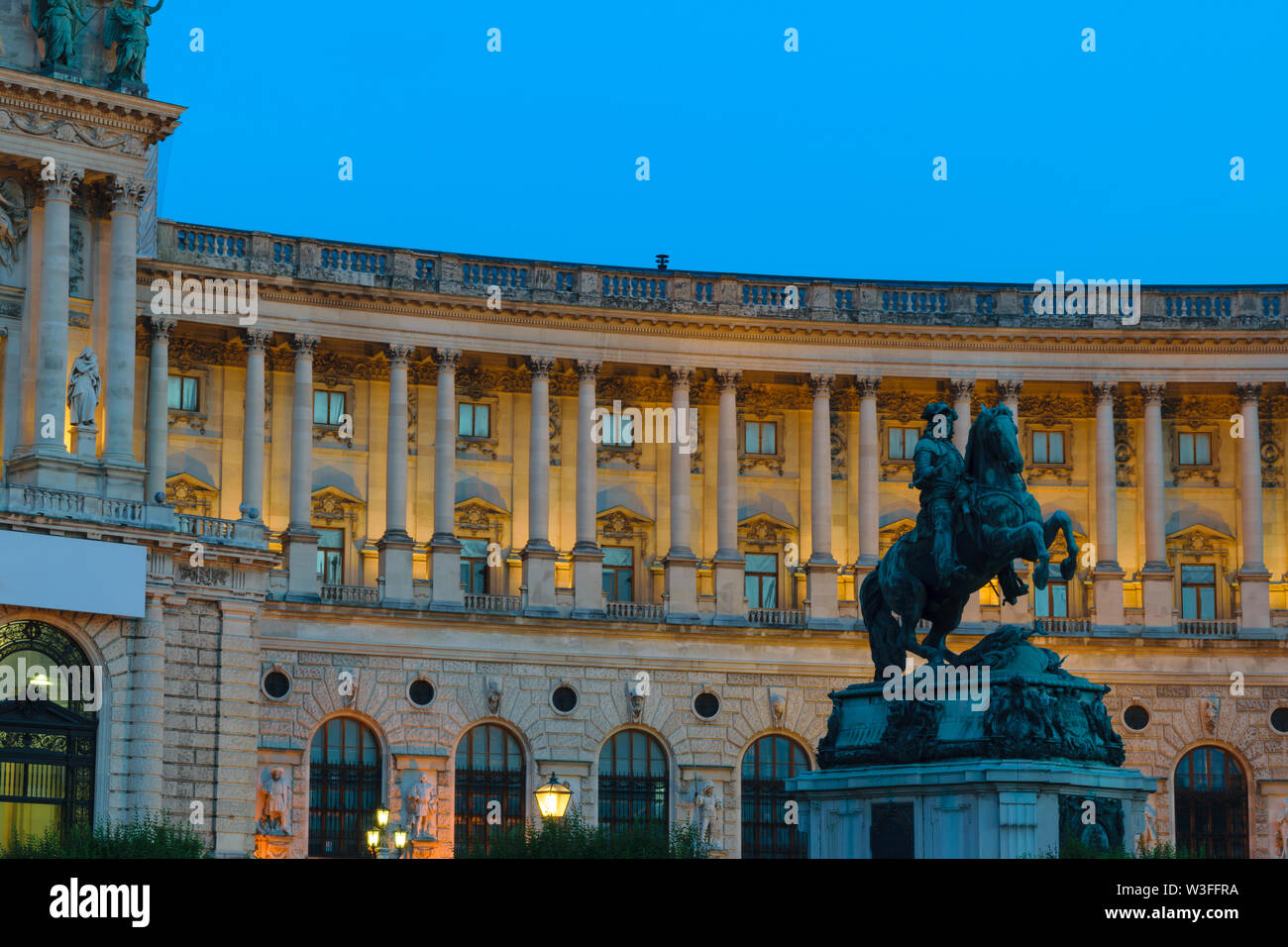 Hofburg palace with statue for prince Eugene von Savoyen during late evening illuminated by yellow light in Vienna, Austria Stock Photo