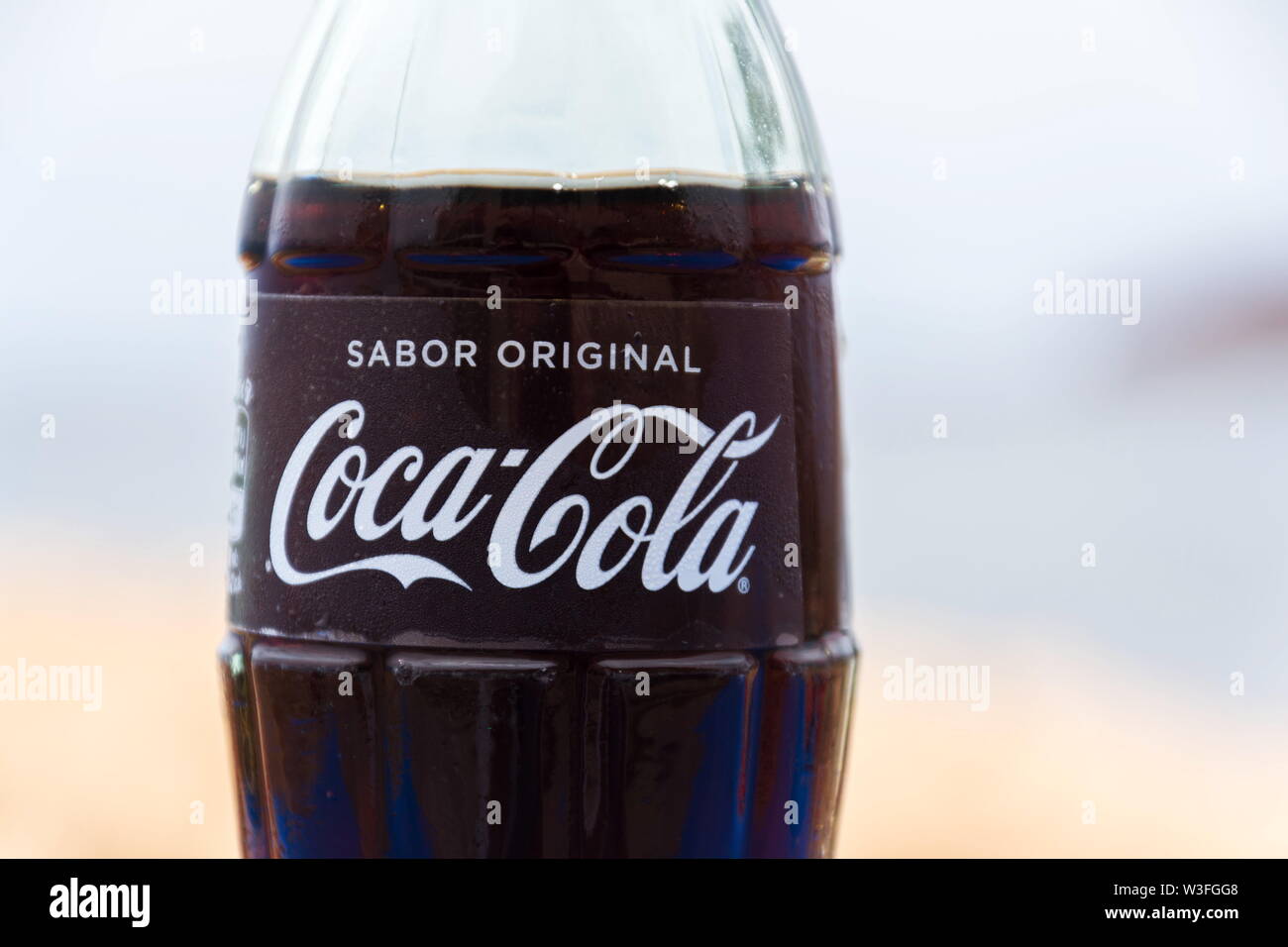 EL MEDANO, SPAIN - JULY 10 2019: Coca-Cola company logo on glass bottle with Coke with sea in background on July 10, 2019 in El Medano, Spain. Stock Photo