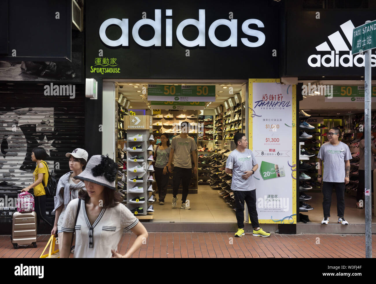 Hong Kong, China. 12th July, 2019. Pedestrians walk by a large Adidas logo  and German multinational sportswear shop in Hong Kong. Credit: Budrul  Chukrut/SOPA Images/ZUMA Wire/Alamy Live News Stock Photo - Alamy