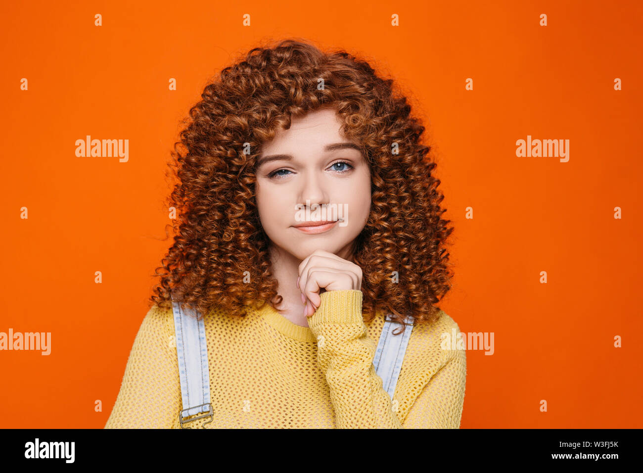 Cute red-haired woman with curly hair skeptical looking, raising one eyebrow. Stock Photo