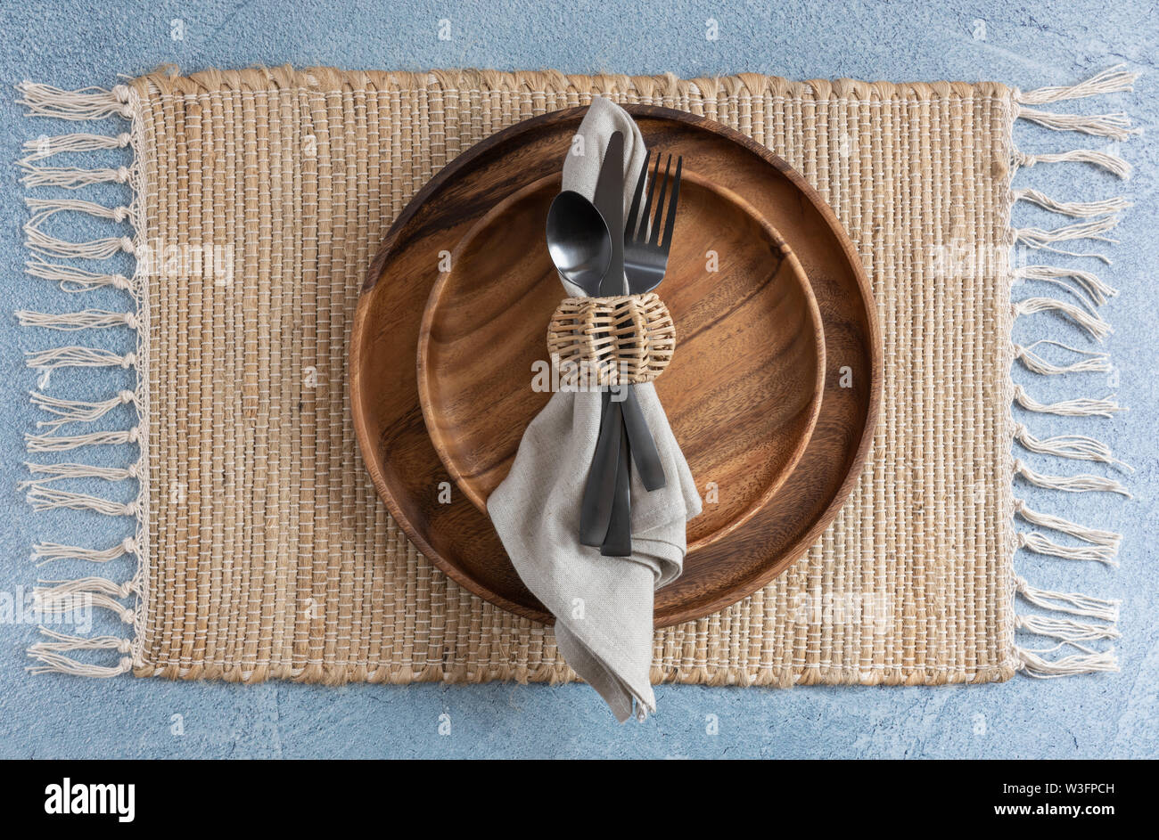 place setting on woven fiber placemat on blue background with two