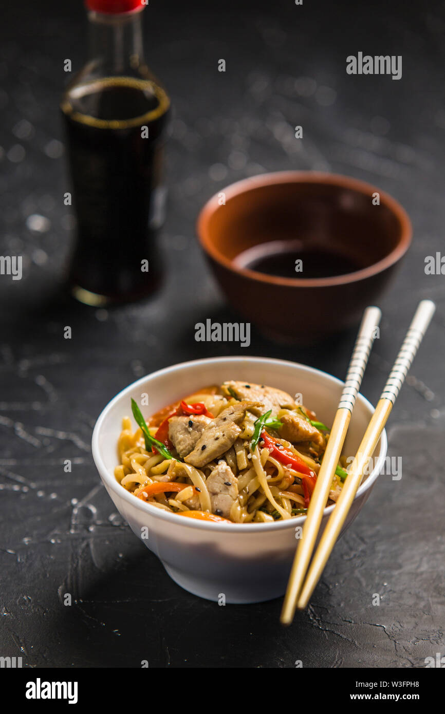 Chinese noodles in a Cup with chicken and vegetables with sticks. Wok