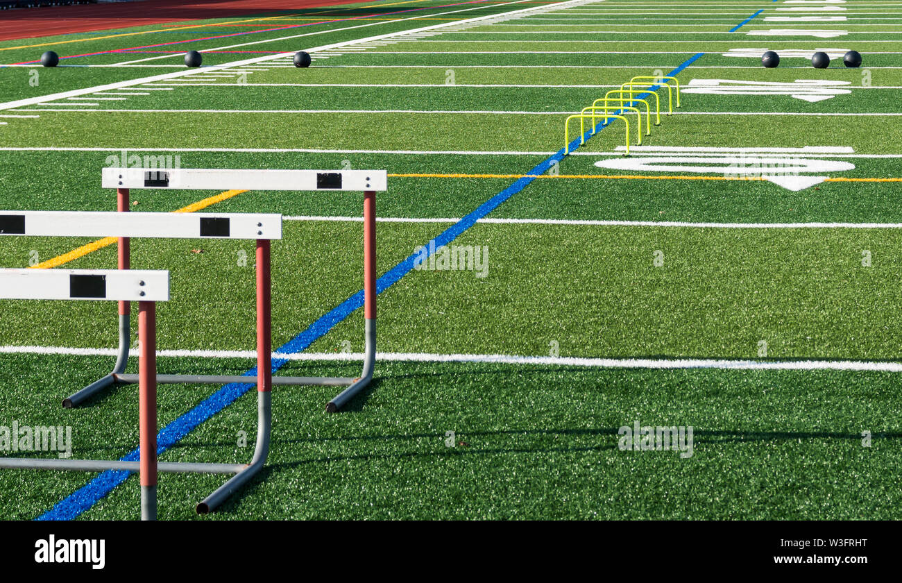 Athletic turf field set up for speed, strength and agility practice with hurdles, medicine balls and mini yellow banana hurdles. Stock Photo