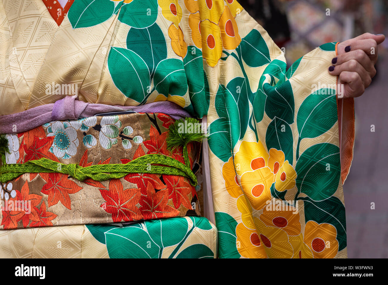 Young girl wearing Japanese kimono standing on a street in a city. Kimono is a Japanese traditional garment Stock Photo