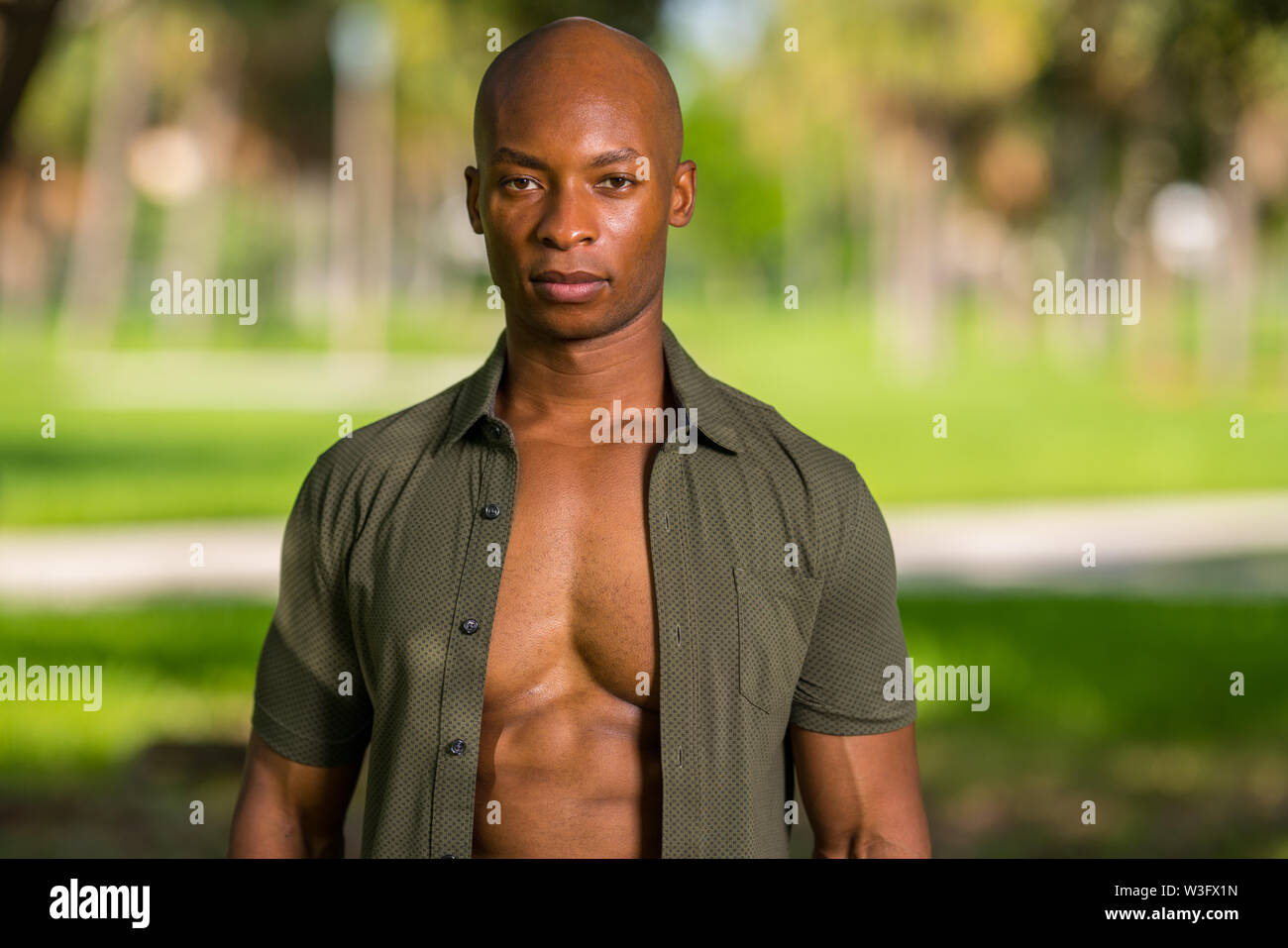 Portrait of an attractive bald young black man with shirt unbuttoned to show muscular chest Stock Photo