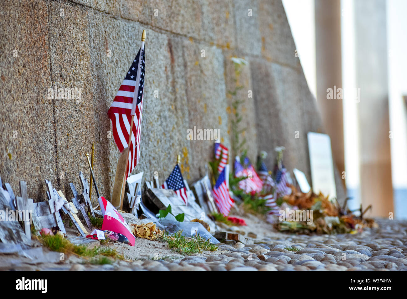 United States and Canadian flags, flowers and objects in memory of fallen in Normandy landing. Omaha Beach Memorial. France. Stock Photo