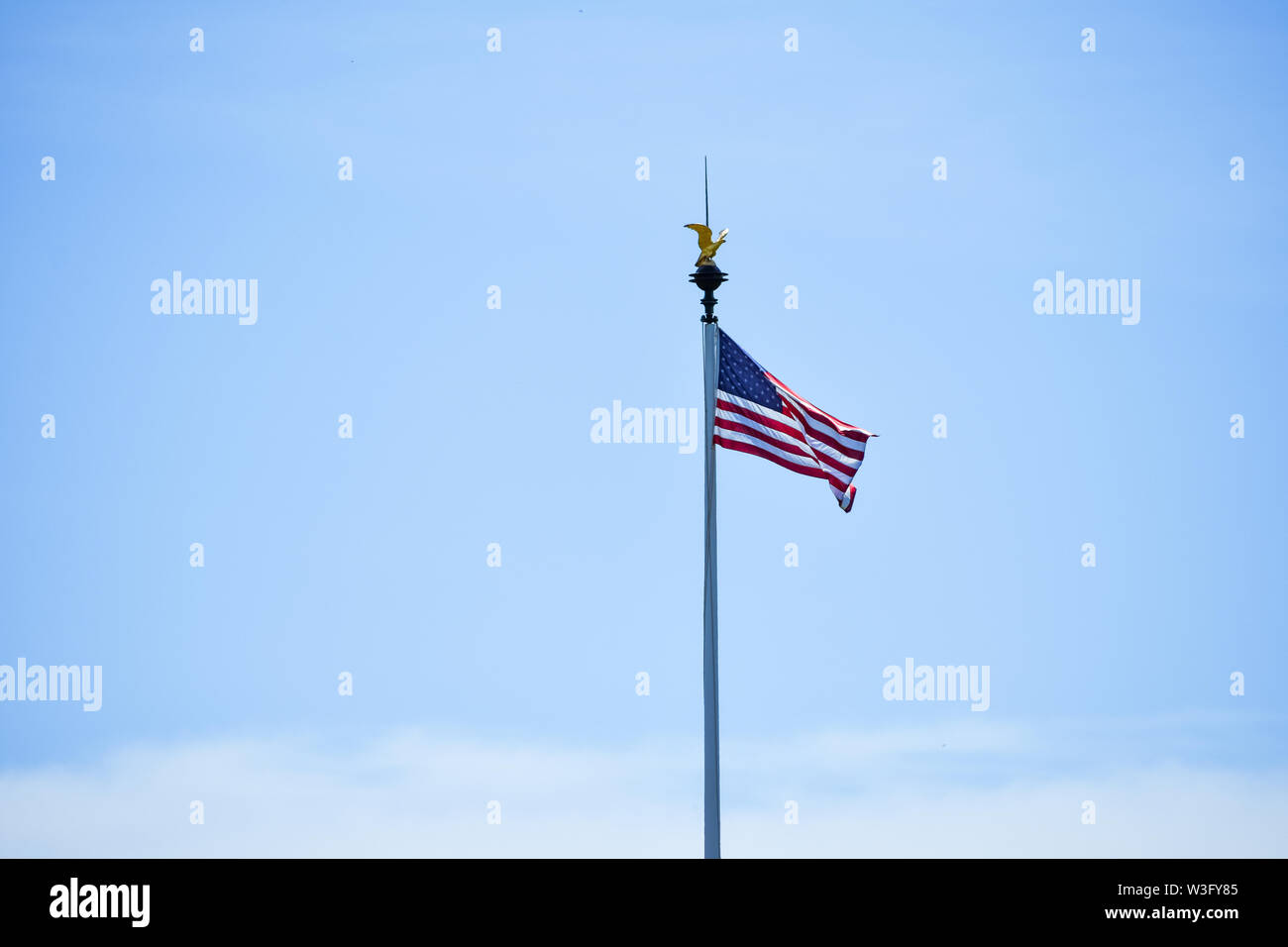 Isolated United States flag waving in the wind in a blue sky background. Copy space for text. Stock Photo