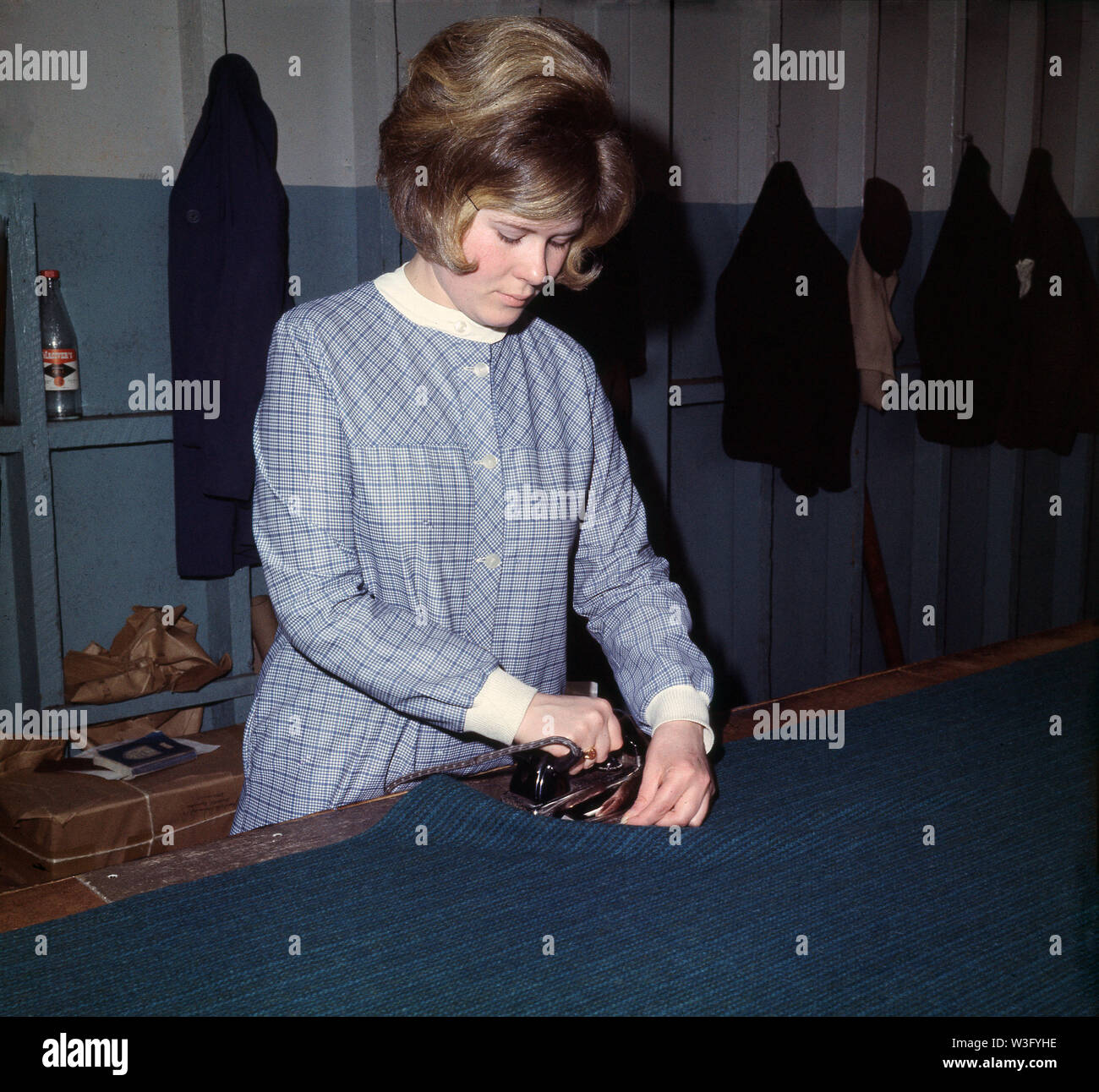 1960s, historical, a young lady 'stamping' Harris Tweed, Stornoway, Lewis, HIghlands, Western Isles, Outer Hebrides, Scotland. The famous Orb stamp or trademark is ironed on to the fabric as a seal of authenticity. Stock Photo