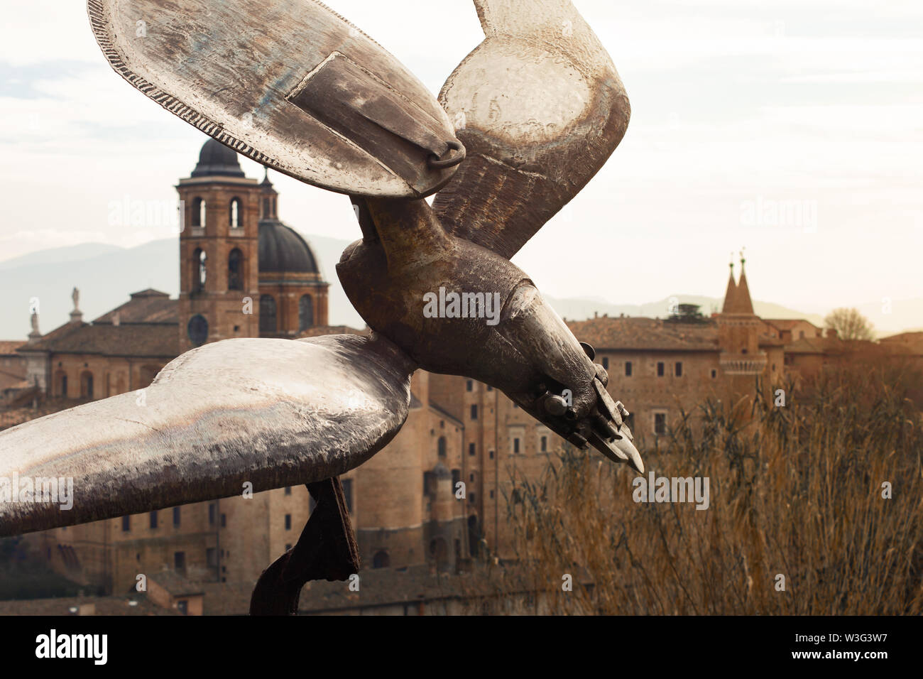 Iron eagle sculpture in Urbino, Marches, Italy. Ducal Palace with towers in background. View from the hill Stock Photo