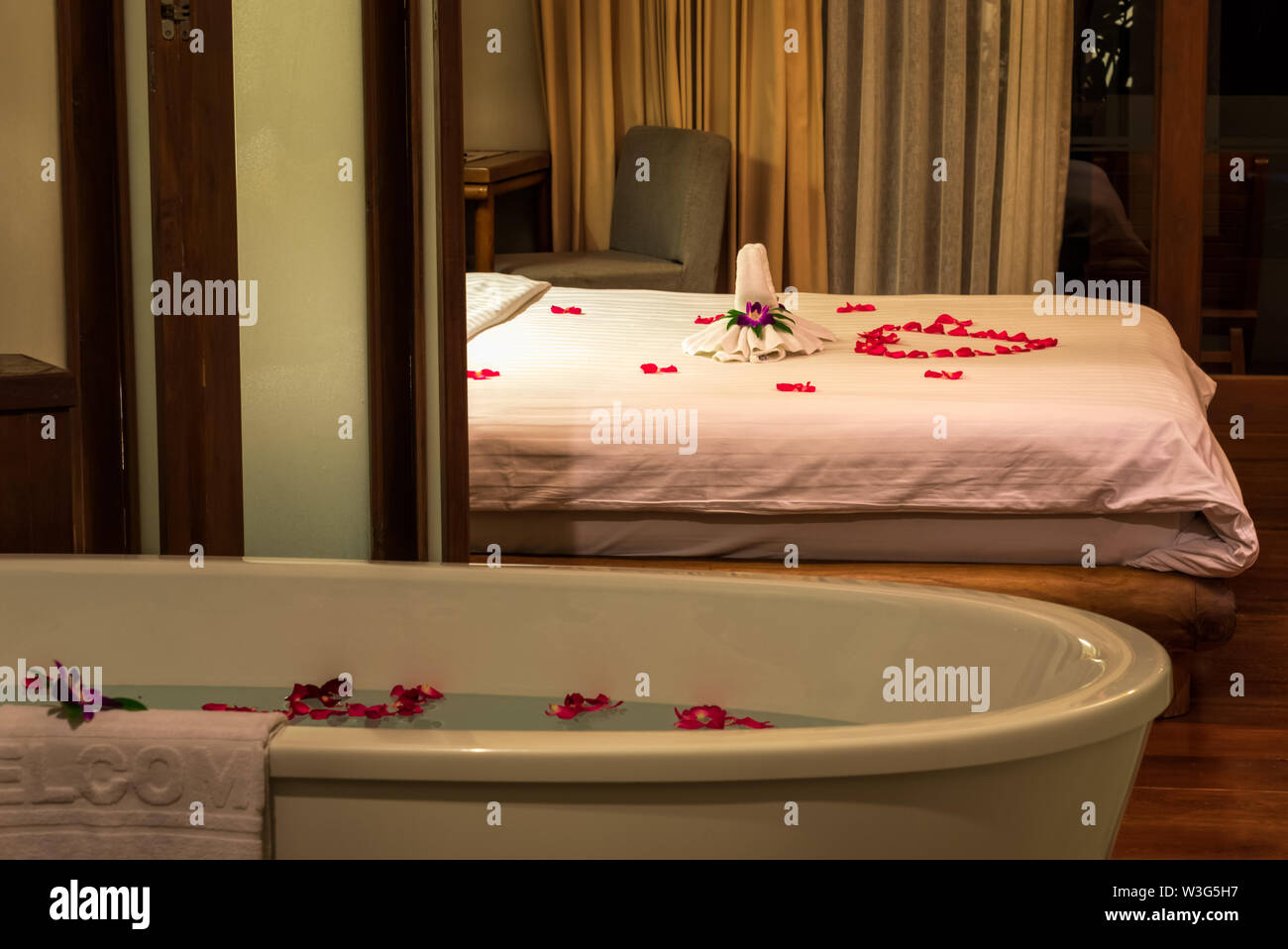 Towels, flowers and red rose petals decorations on the bed