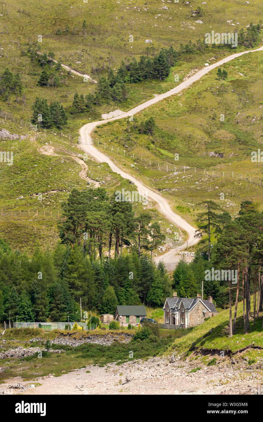 Workers cottage in Glen Strathfarrar, by the shore of Loch Morar, showing a Scottish hill track behind, which was created by the estate. Stock Photo