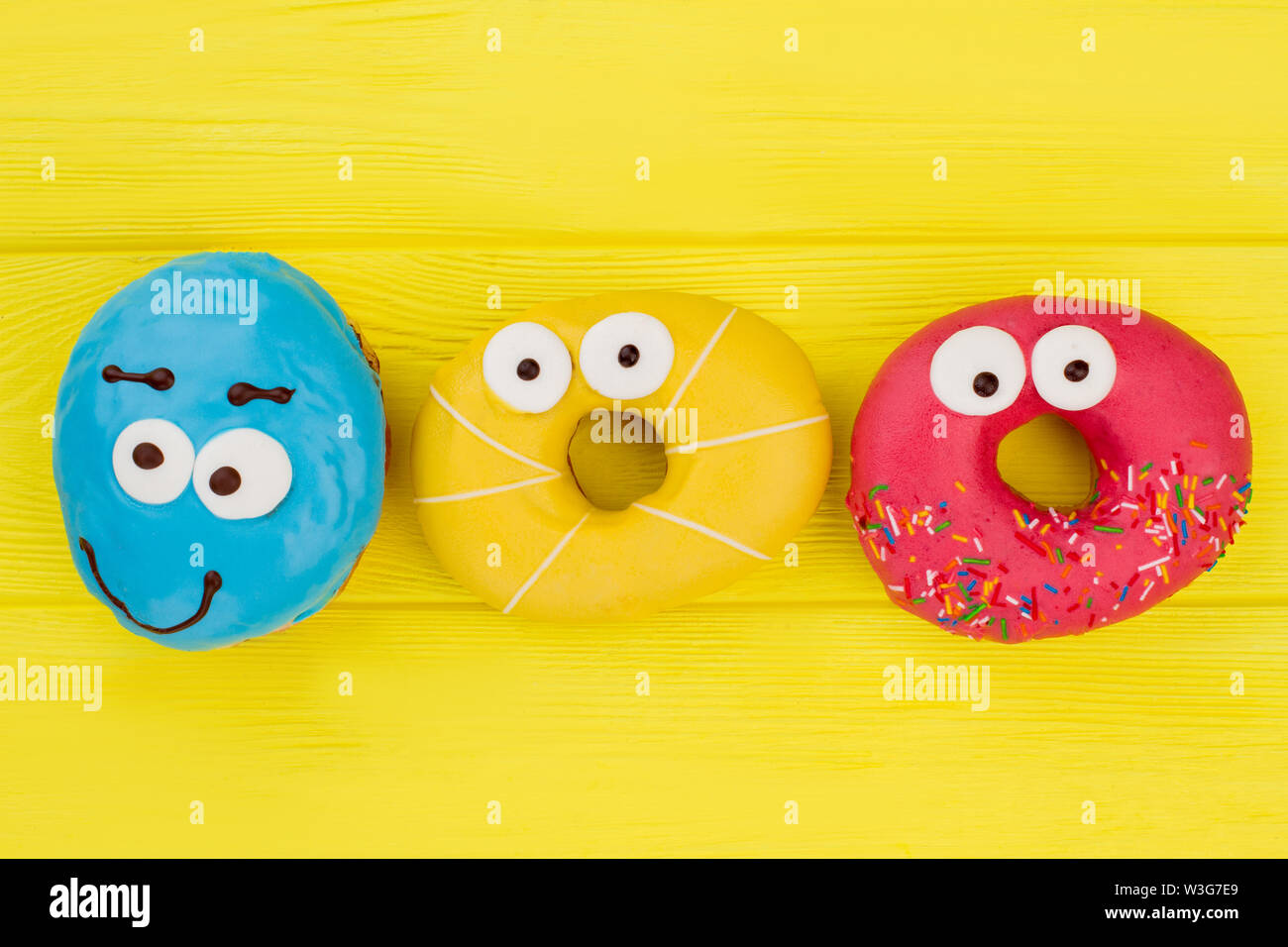Funny colorful donuts on yellow background. Stock Photo