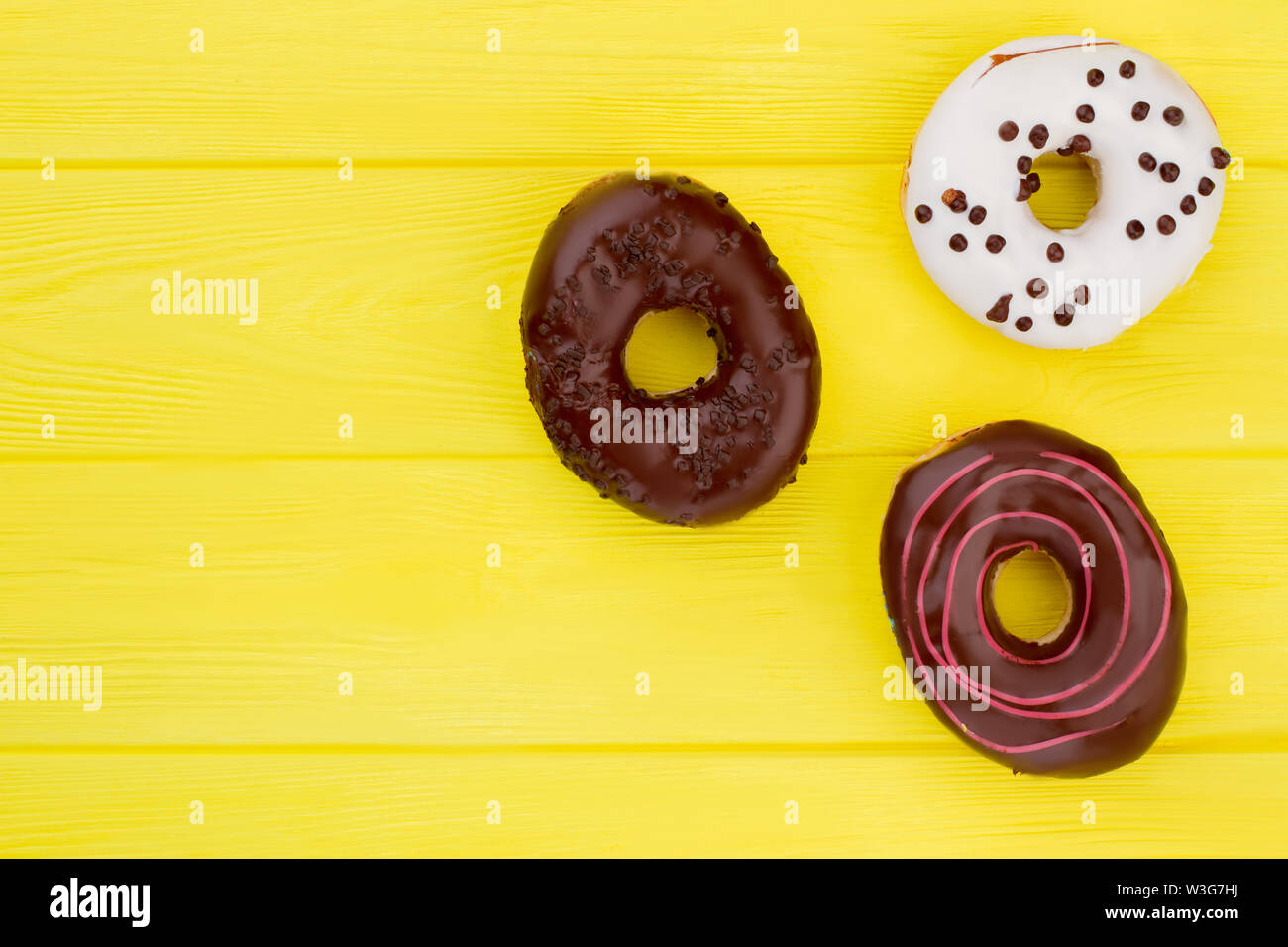 Three different donuts on yellow background. Stock Photo
