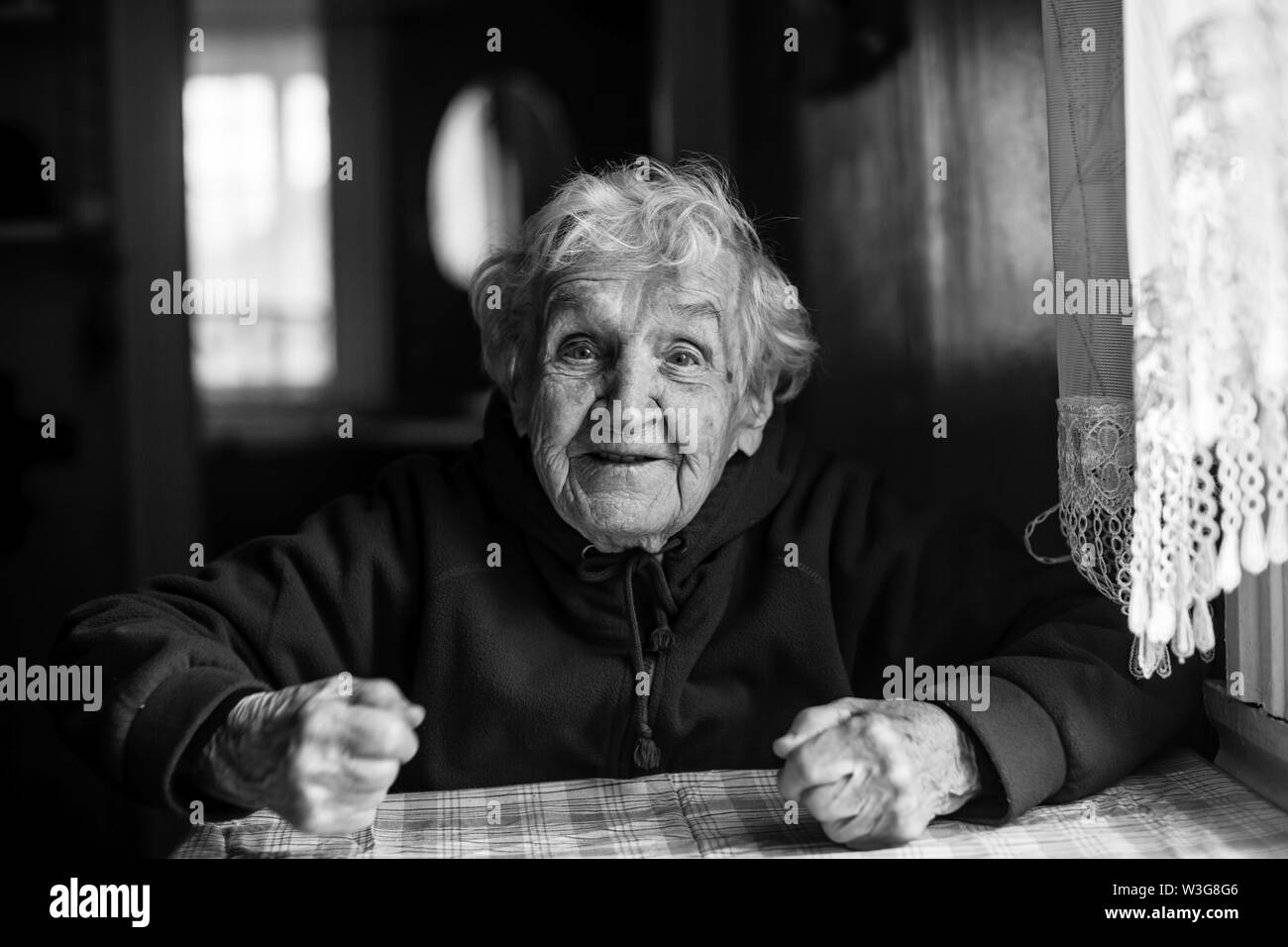 Portrait of an emotional old woman in her house. Black and white photo ...
