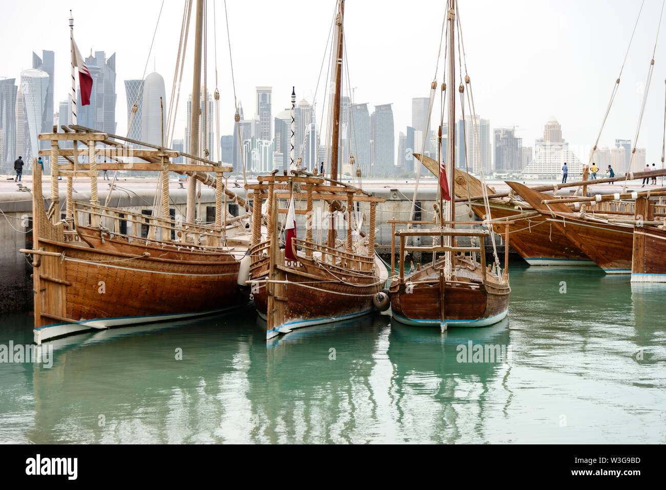 Traditional dhows with flags of Qatar are docked in harbor of Doha, such vessels are popular for tourist trips along the coast, Qatar, Middle East. Stock Photo