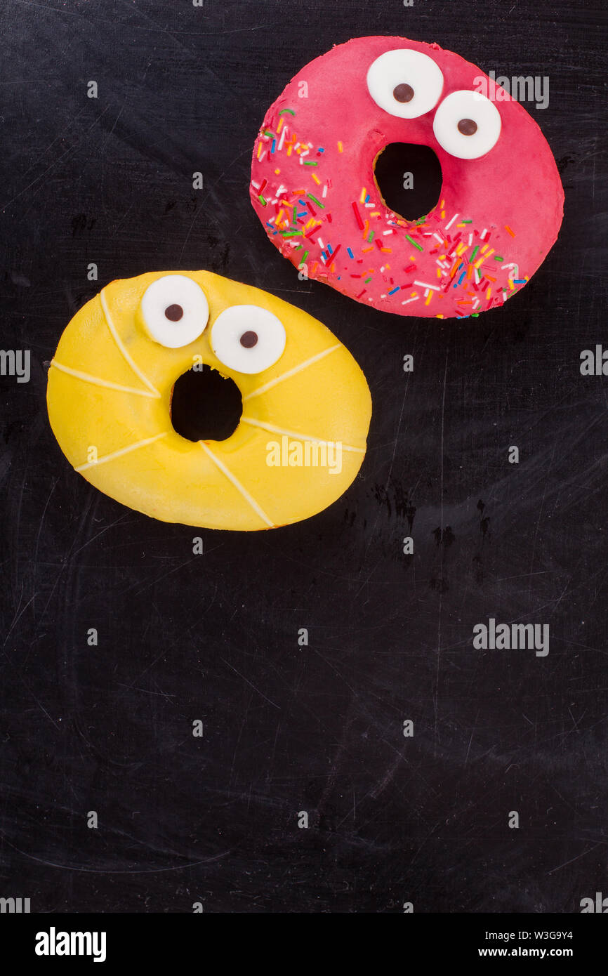 Funny donuts on black background, top view. Stock Photo