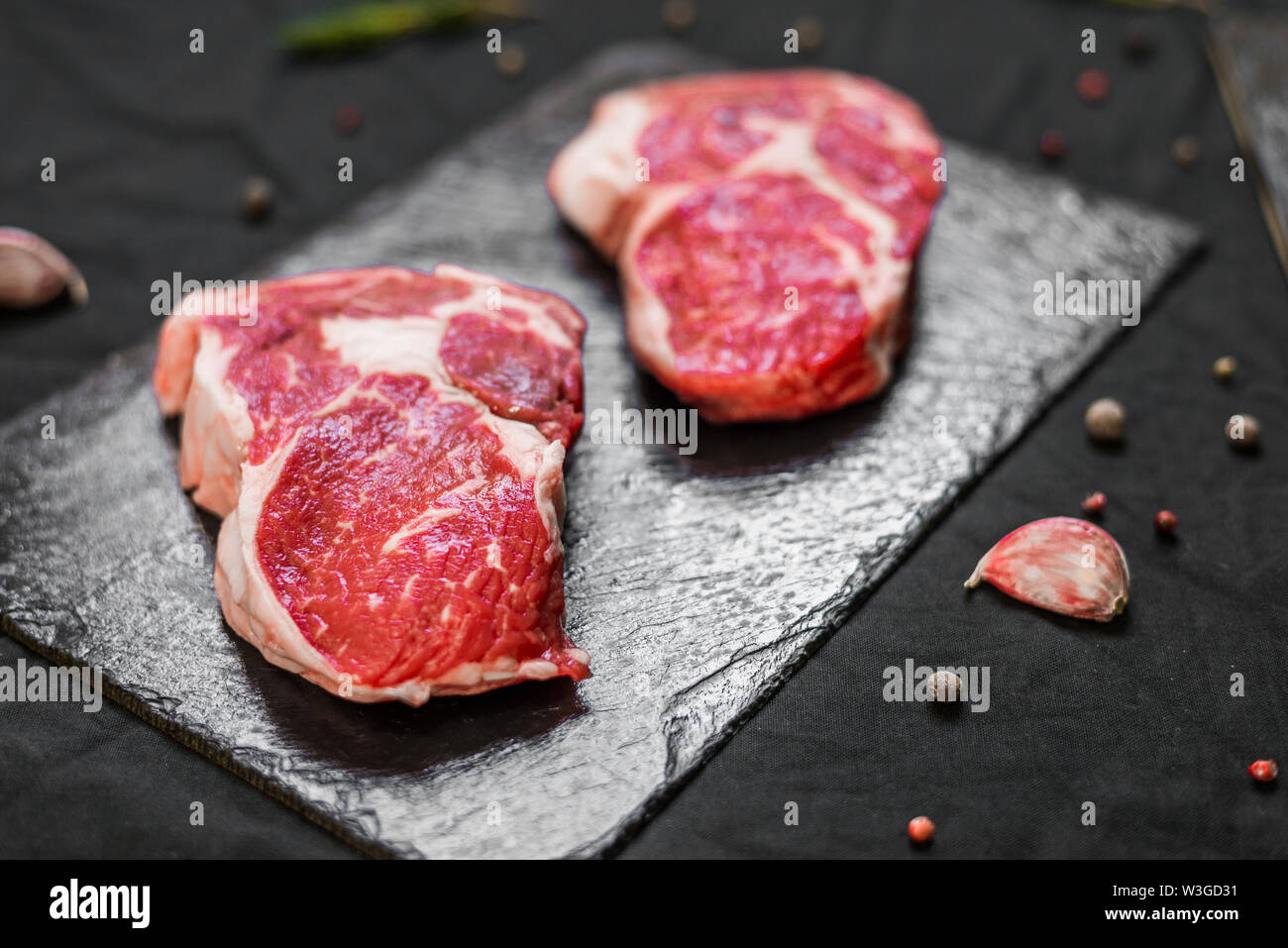Rib eye beef cow steak meat with spices and herbs against black