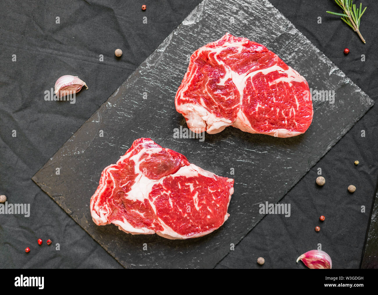 Rib eye beef cow steak meat with spices and herbs against black ...