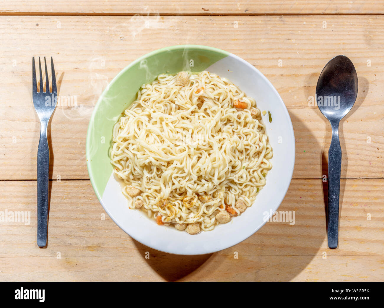 Noodles on the bowl with spoon and fork on wooden table background Stock Photo