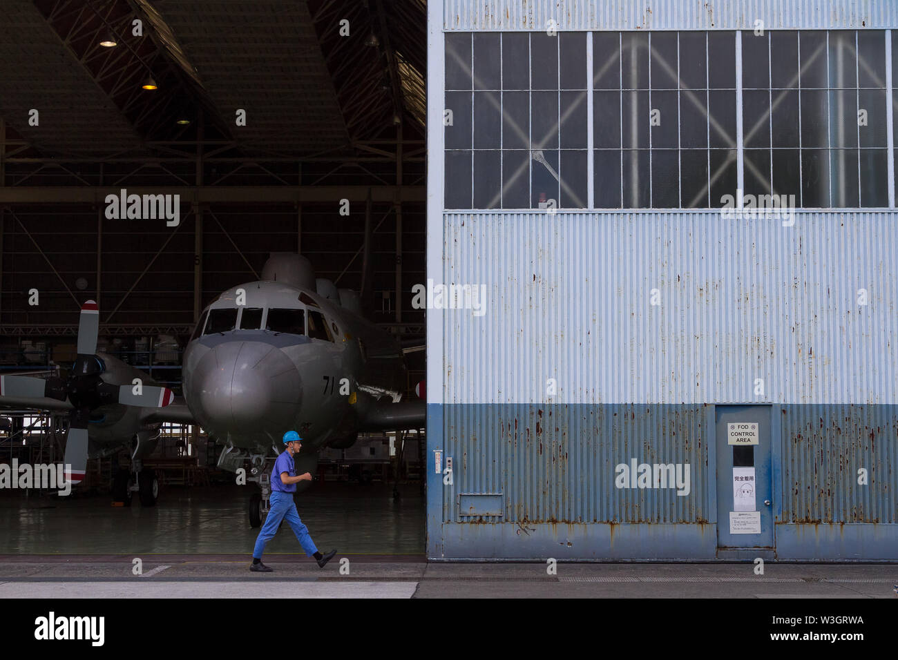 A workman walks past a Lockheed EP3 Orion ELINT signals reconnaissance aircraft being serviced in a hanger on Naval Air Facility, Atsugi airbase, Kanagawa, Japan Stock Photo