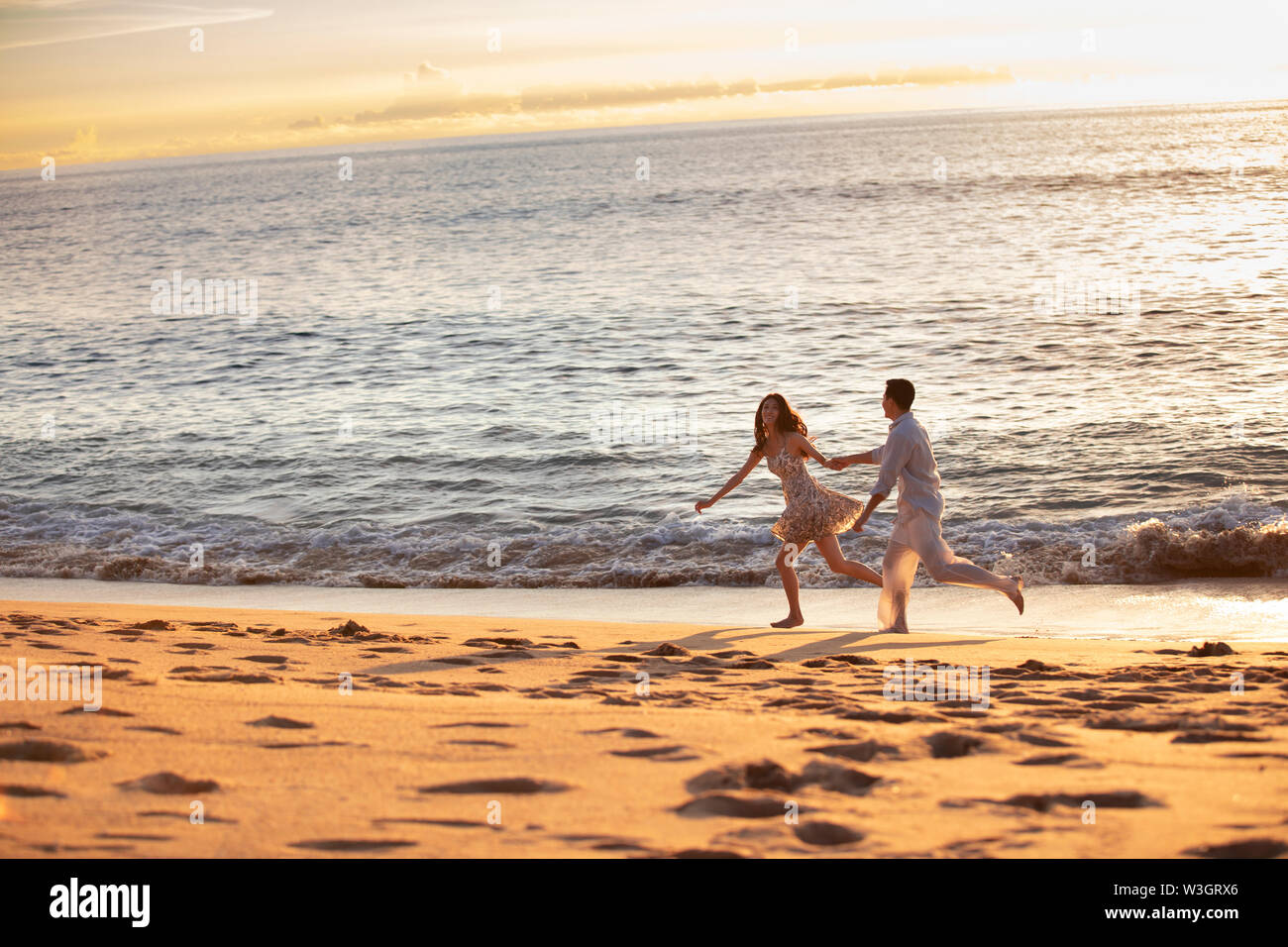 Happy young couple running on beach Stock Photo - Alamy