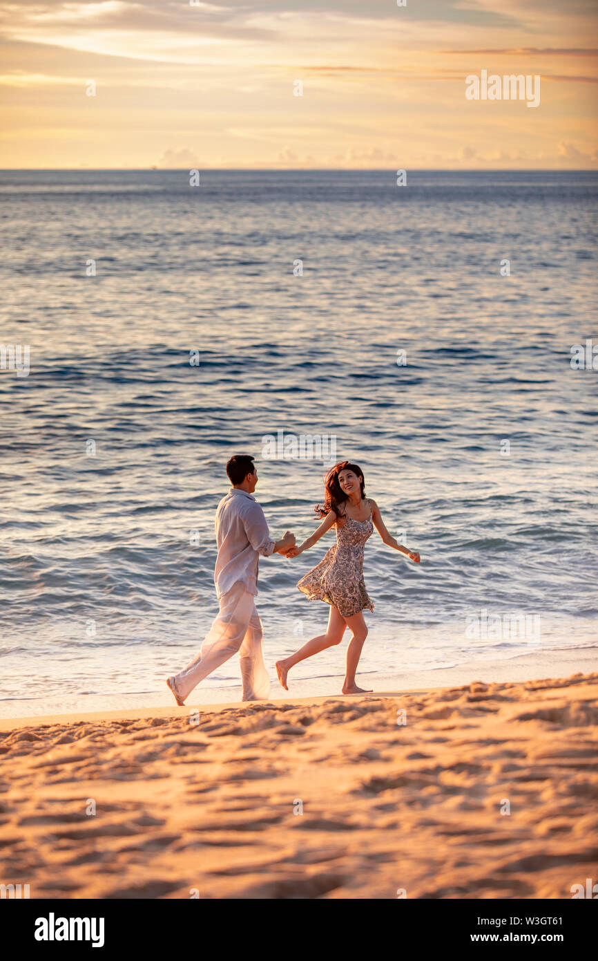 Happy young couple running on beach Stock Photo - Alamy