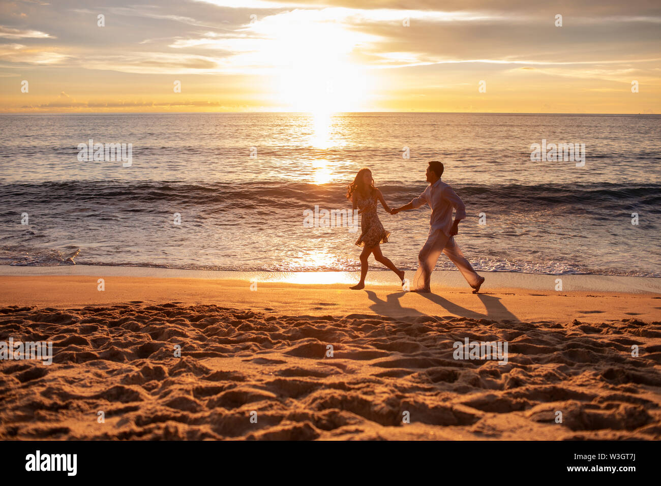Happy young couple running on beach Stock Photo - Alamy