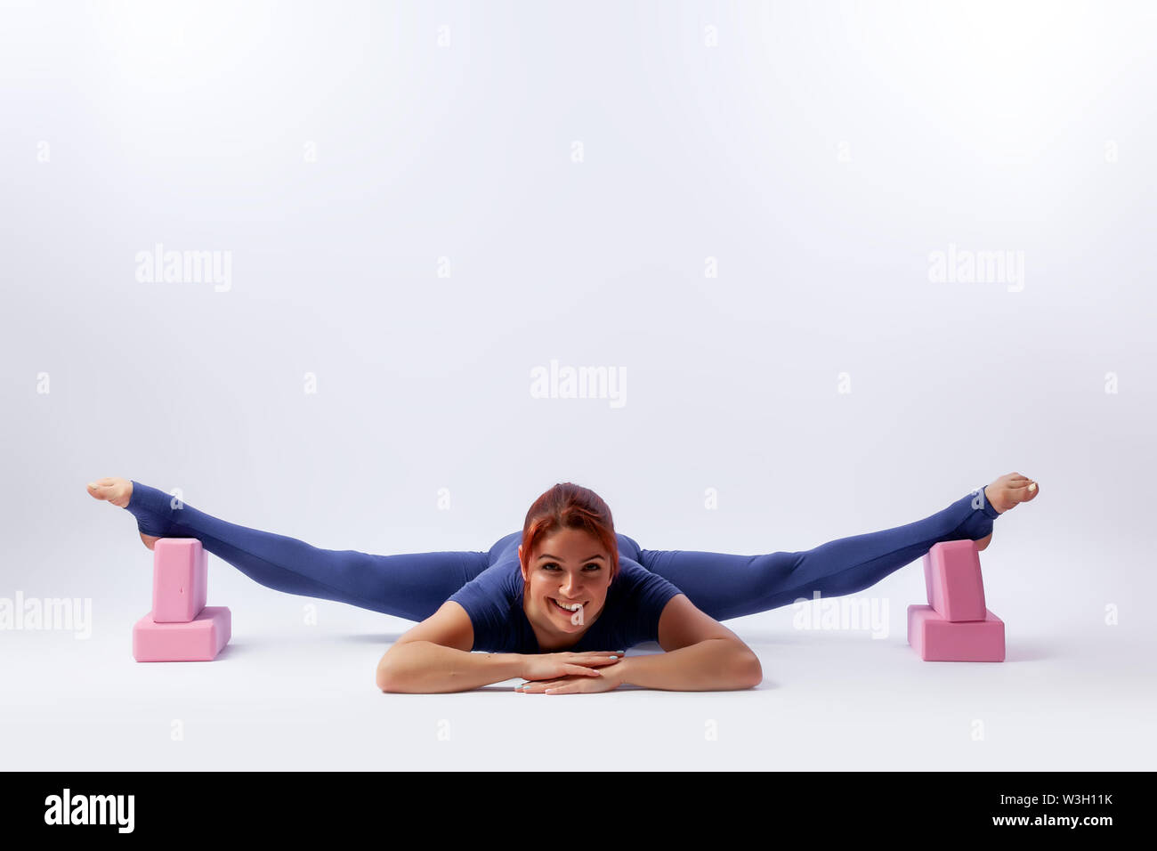 Beautiful slim woman in sports overalls  doing yoga, standing in an asana pose - twine  on white  isolated background. The concept of sports and medit Stock Photo
