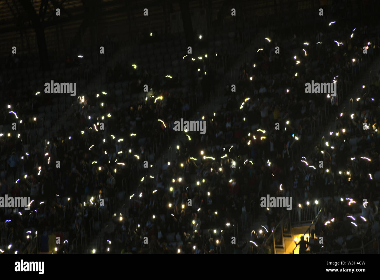 Motion blur of crowd of glowing smart phones in a dark stadium tribune Stock Photo