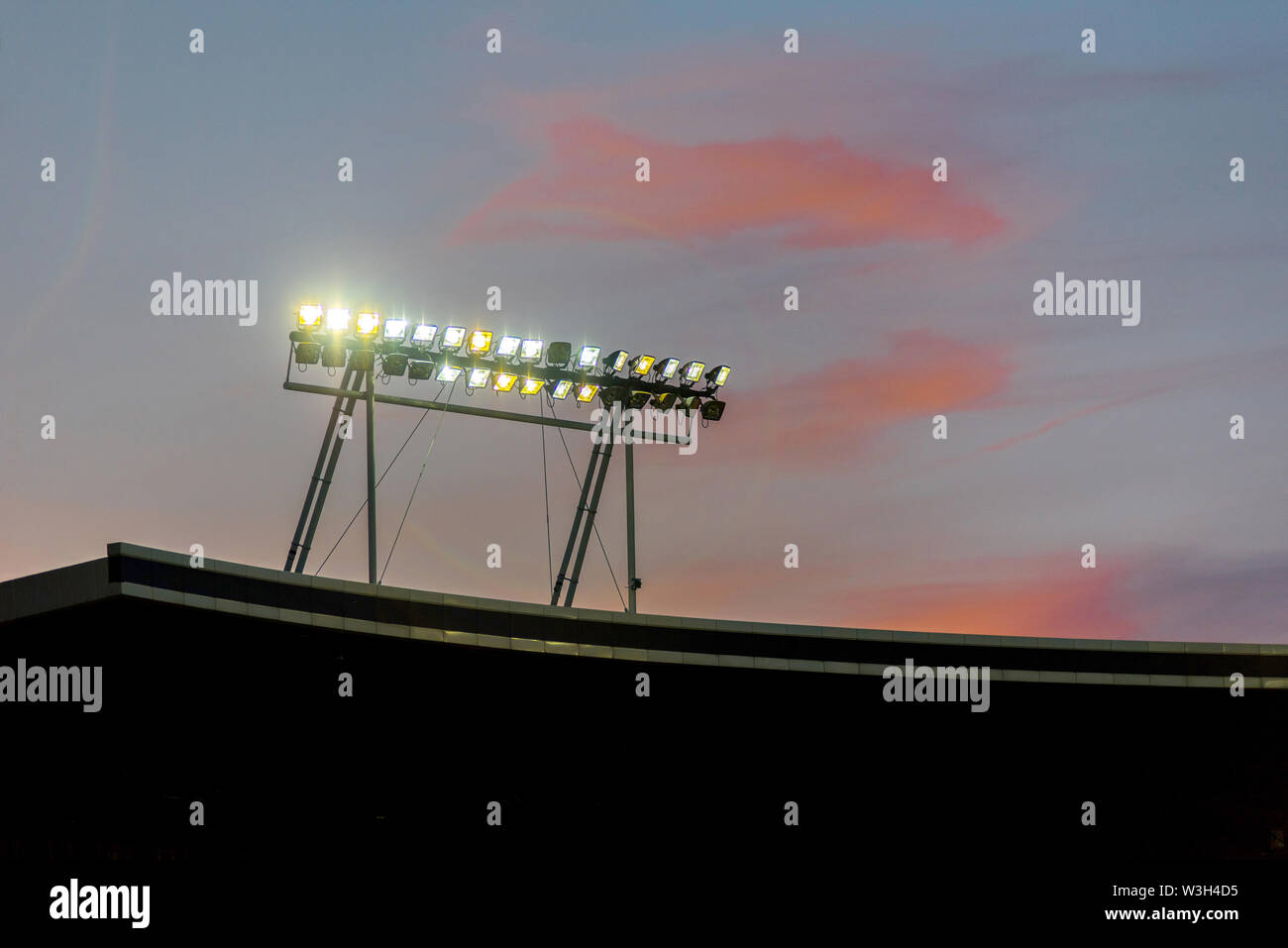 Stadium lights against blue sky during sunset Stock Photo