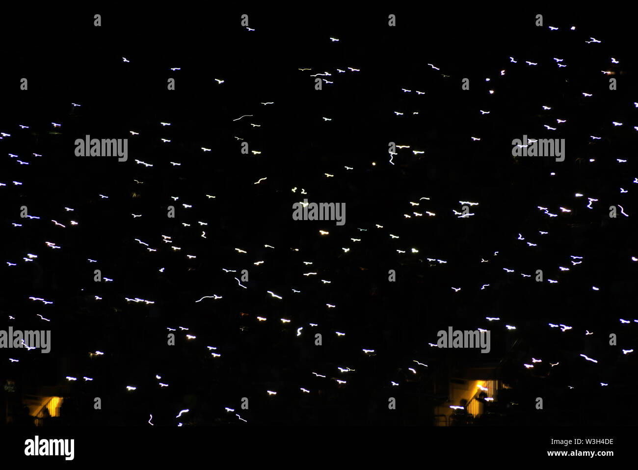 Motion blur of crowd of glowing smart phones in a dark stadium tribune Stock Photo