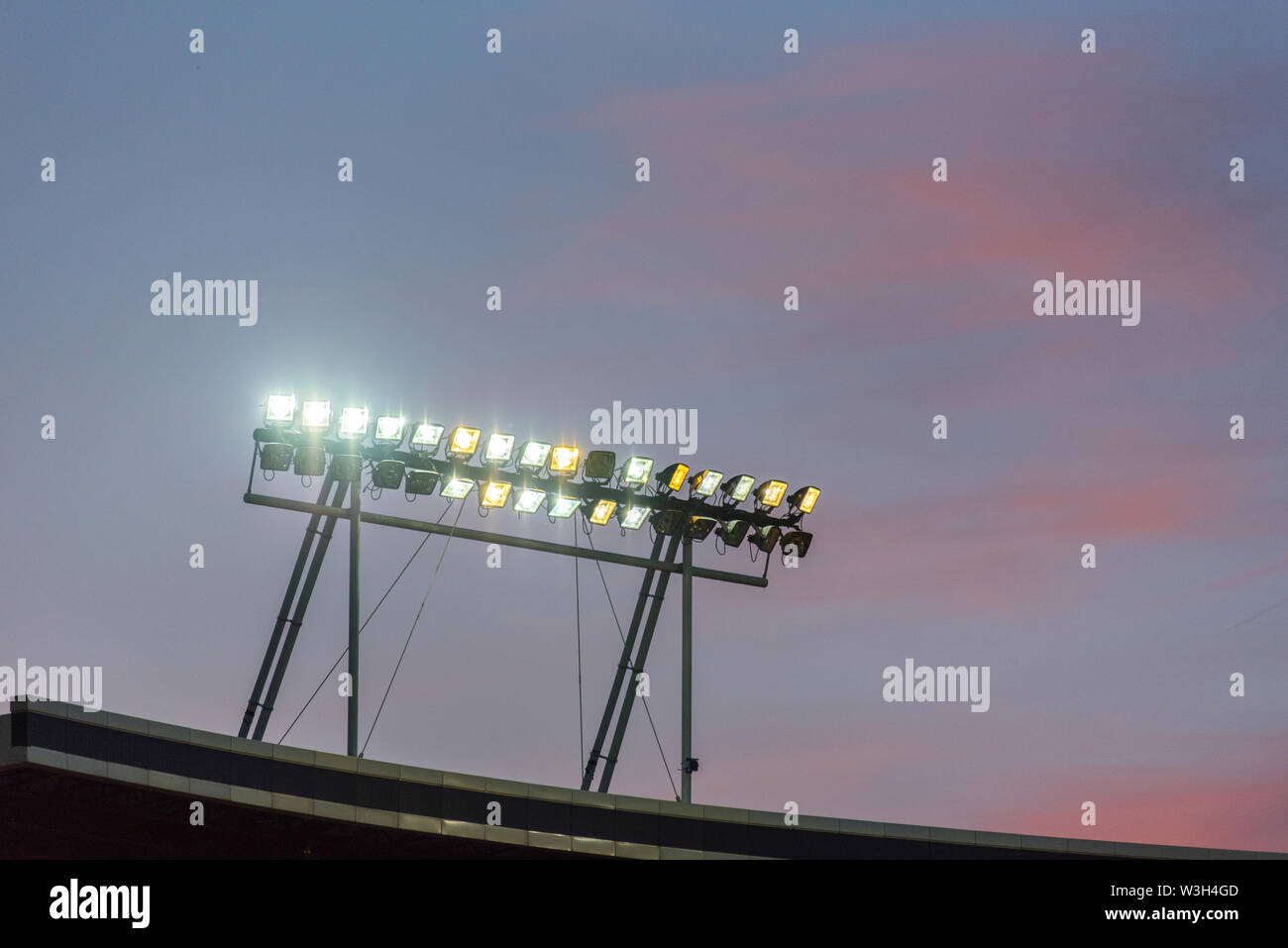 Stadium lights against blue sky during sunset Stock Photo