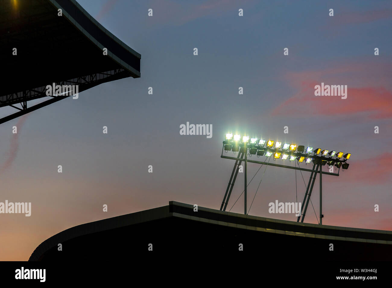 Stadium lights against blue sky during sunset Stock Photo