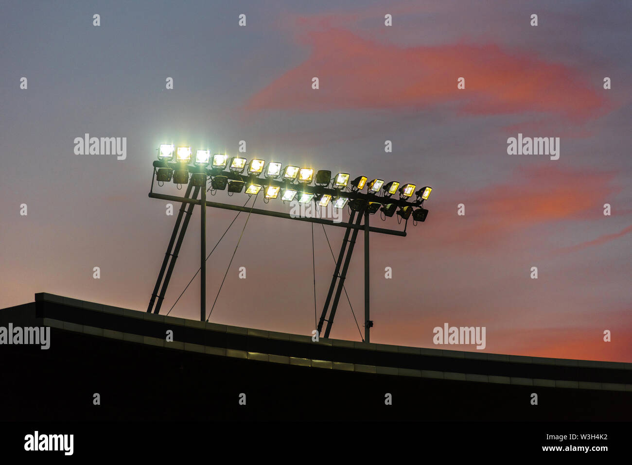 Stadium lights against blue sky during sunset Stock Photo