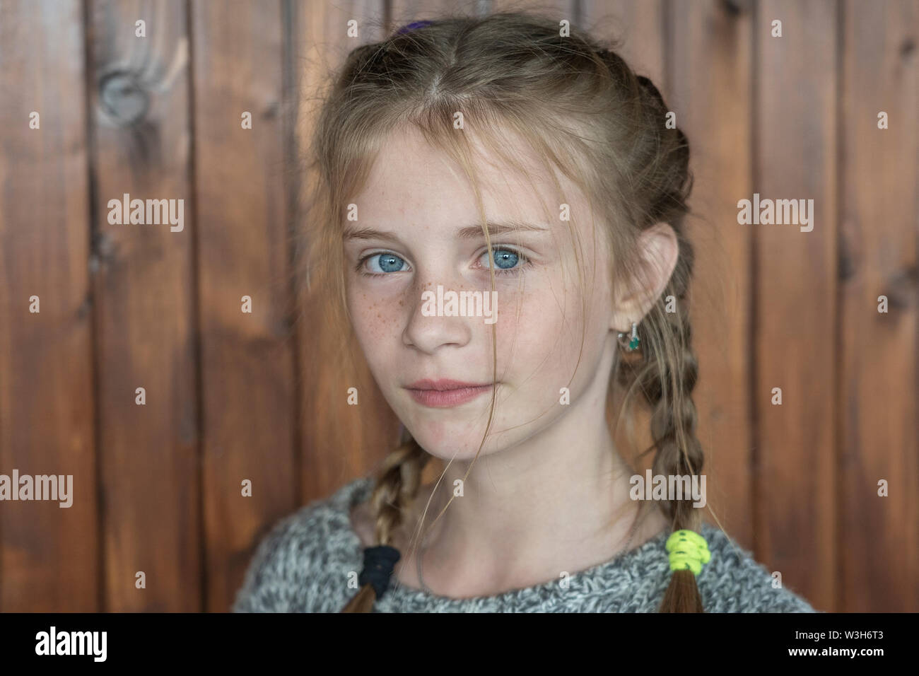 Beautiful blonde young girl with freckles indoors on wooden background, close up portrait Stock Photo