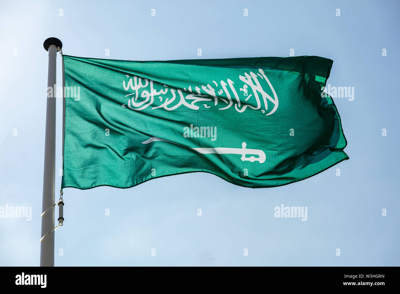 Saudi Arabia flag, National symbol waving against clear blue sky, sunny day Stock Photo