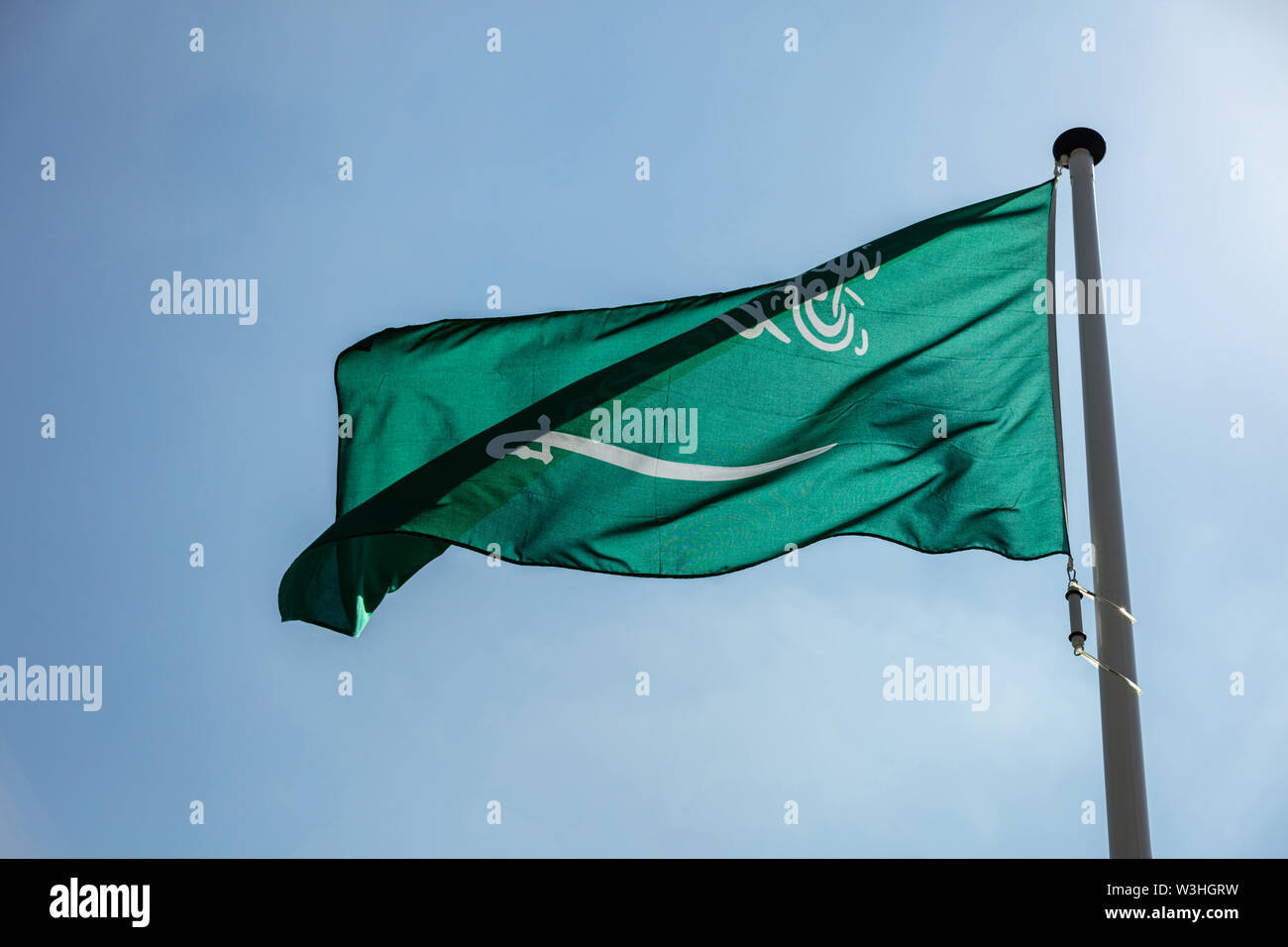 Saudi Arabia flag, National symbol waving against clear blue sky, sunny day Stock Photo