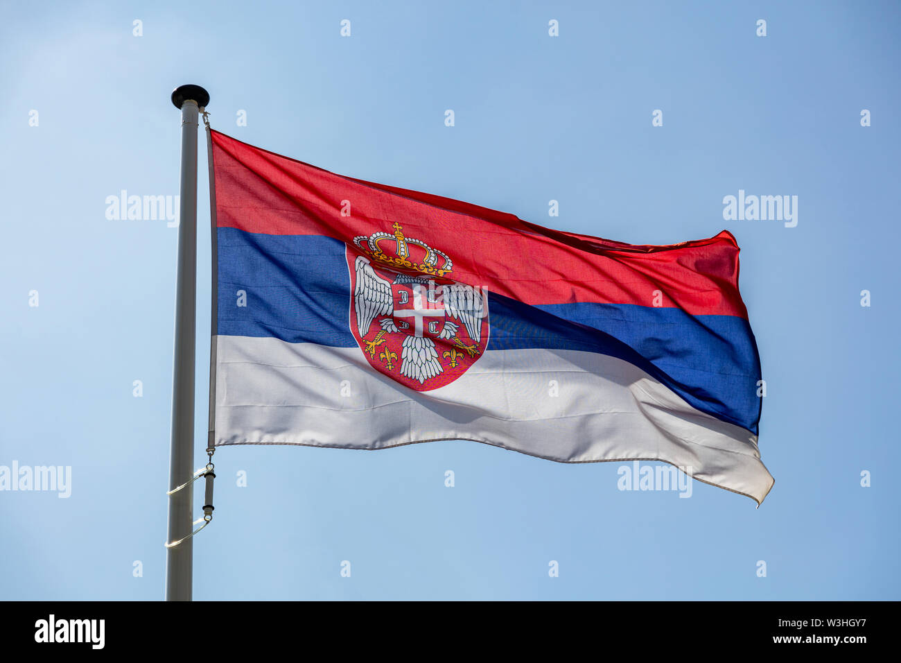 Serbia flag, National symbol waving against clear blue sky, sunny day Stock Photo