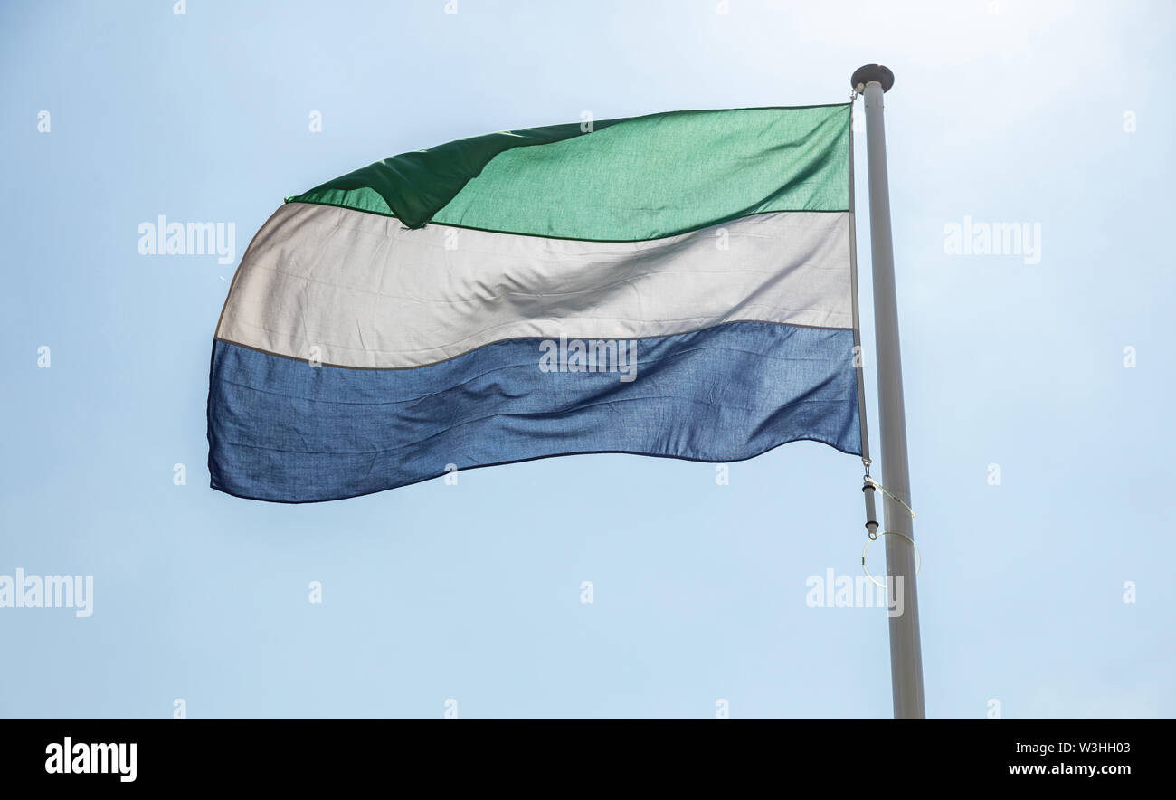 Sierra Leone flag, National symbol waving against clear blue sky, sunny ...