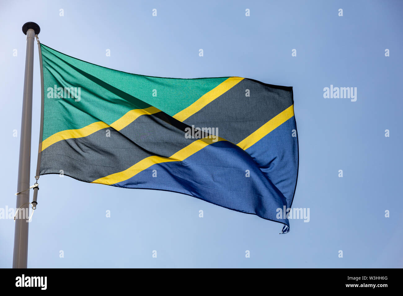 Tanzania flag, National symbol waving against clear blue sky, sunny day